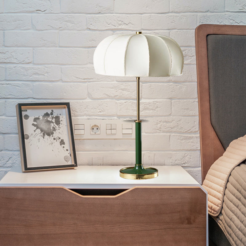Green Demolights Mid Century Modern table lamp with sleek design, featuring a round base and cylindrical shade on a wooden table.