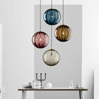 Clear glass ball pendant lamp by DEMOLIGHTS hanging from ceiling with visible cord, modern lighting fixture for stylish interior decor.