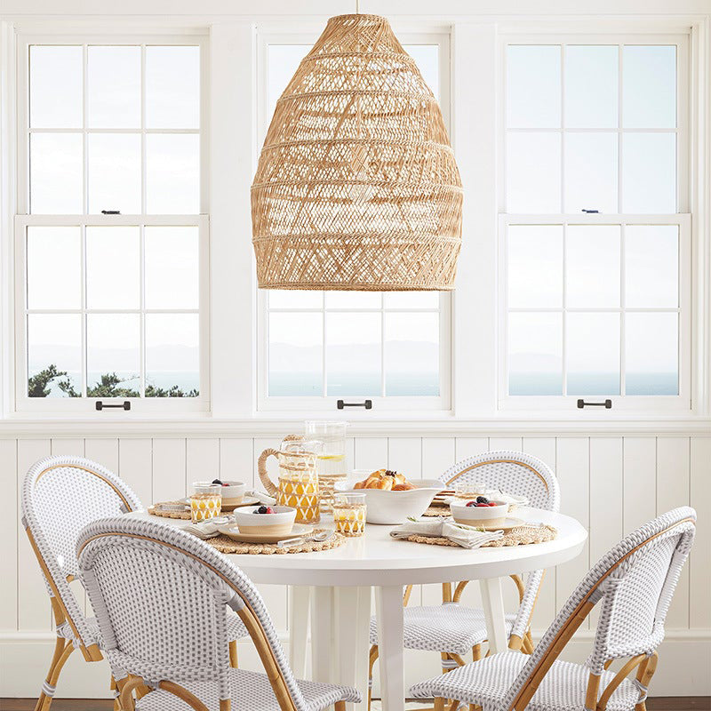 Rattan woven basket pendant lamp shade by DEMOLIGHTS hanging with a warm glow, ideal for rustic or boho interior lighting.